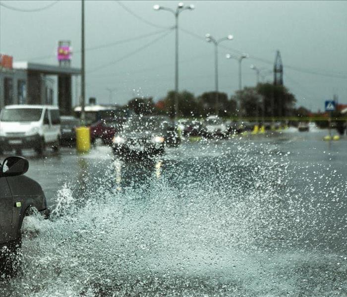 Image of a flooded street and a car driving through